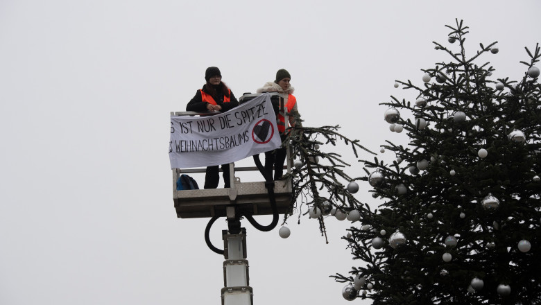 Doua activiste de mediu au taiat cu un fierastrau varful bradului de Craciun din fata Portii Brandenburg, din Berlin Imagine
