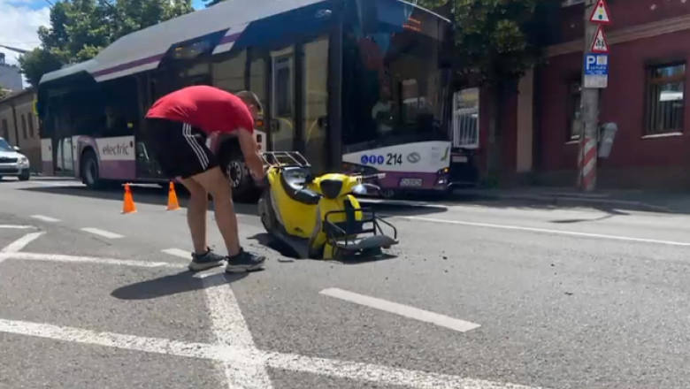 Scuter inghitit pe jumatate de o groapa uriasa nesemnalizata, pe o strada din Cluj Napoca  Imagine
